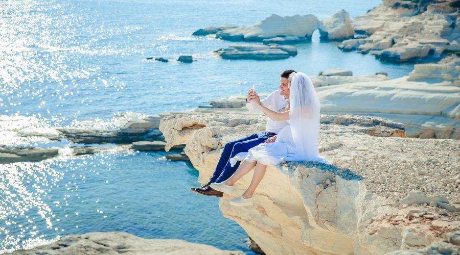 couple de mariés assis du haut d'une falaise surplombant la mer